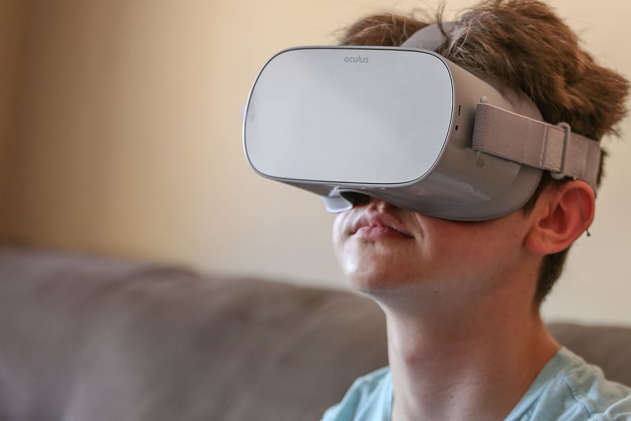 Teenage boy sitting indoors, wearing virtual reality headset HD wallpaper