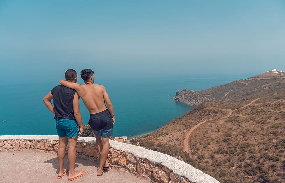 Two Man Standing on Mountain Cliff With Ocean View, back view HD wallpaper
