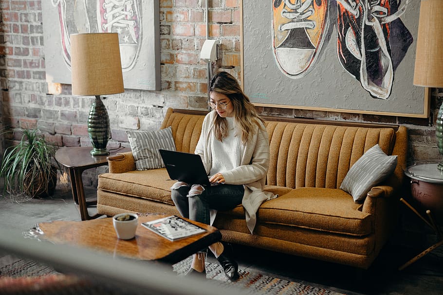 woman using laptop while sitting on chair, couch, furniture, person