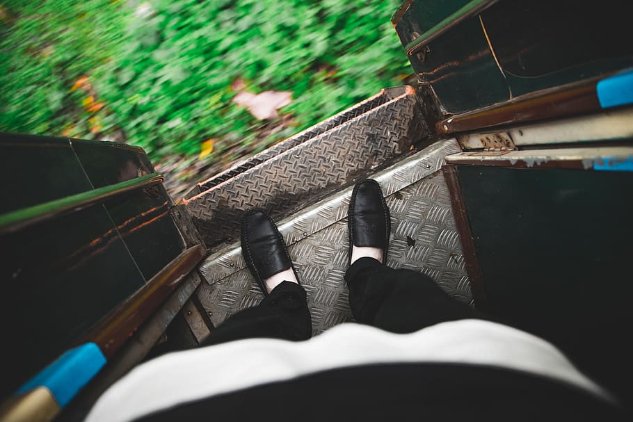 Looking down at feet on the edge of an open entrance door of a running train in Myanmar