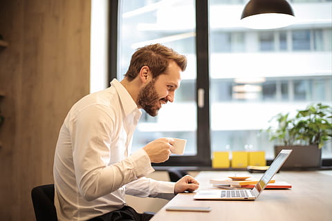 Man Holding Teacup Infront of Laptop on Top of Table Inside the Room HD wallpaper