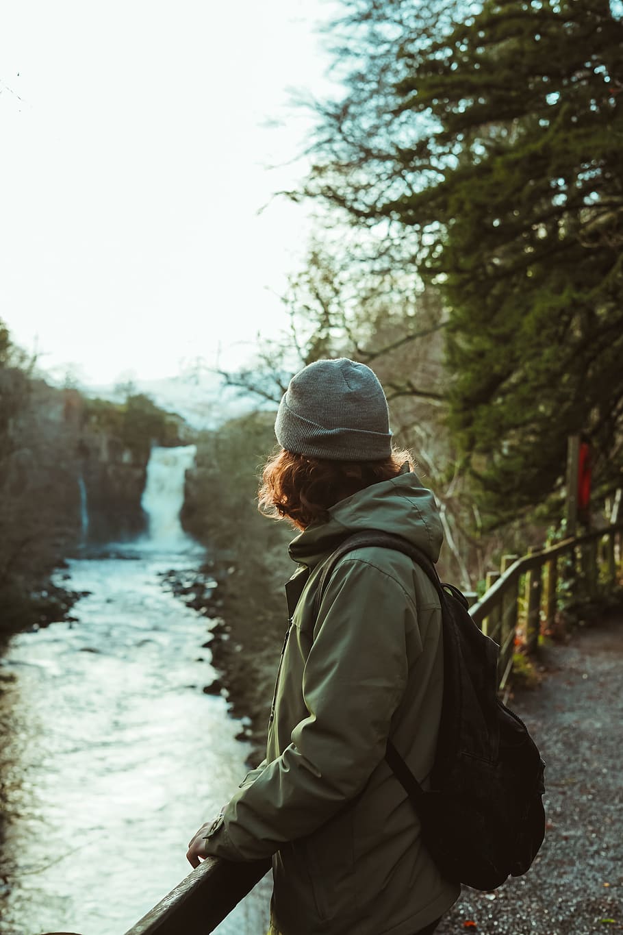 person leaning on bridge above a river, backpack, railing, waterfall HD wallpaper