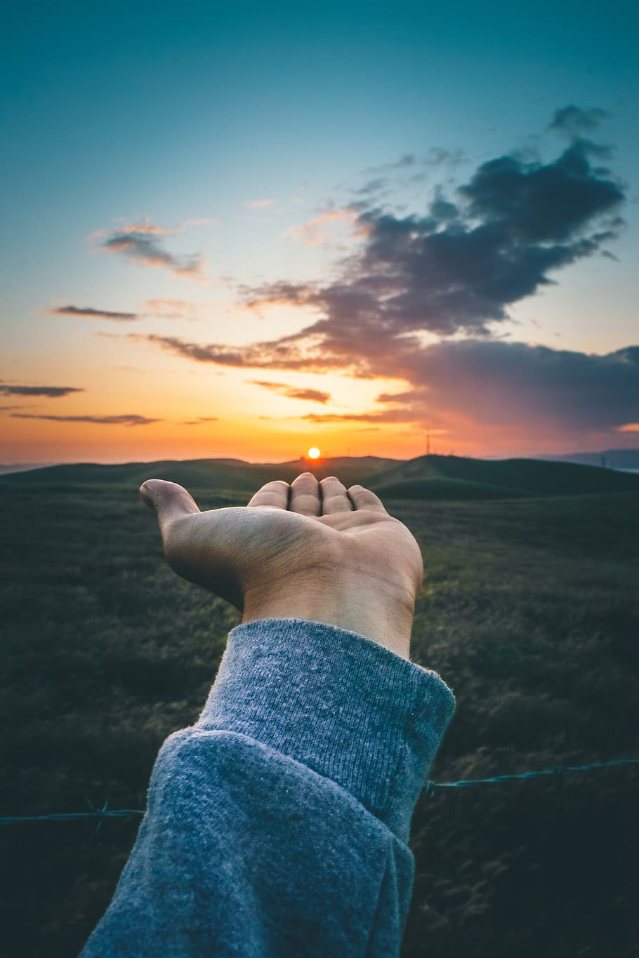 force-perspective photography of person wearing gray long-sleeved shirt carrying sun setting behinds haze HD wallpaper