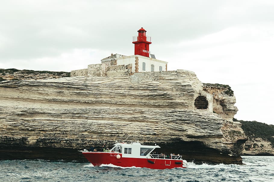 red-and-white-boat-on-body-of-water-near-gray-rock-formation-during-daytime.jpg