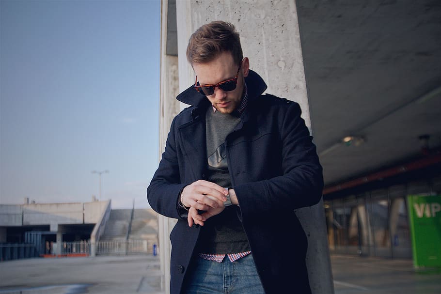 man wearing black coat looking at watch, clothing, apparel, sunglasses