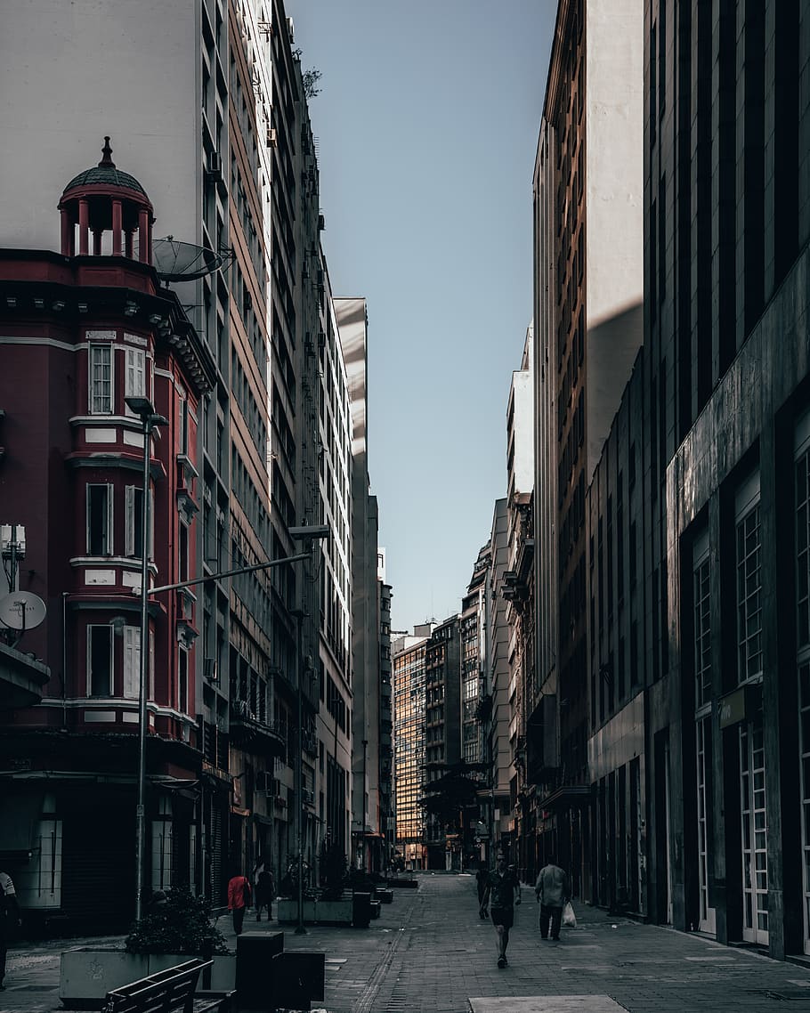 person walking between buildings, brazil, shadow, downtown, urban