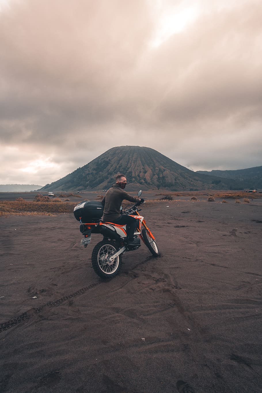 man riding motorcycle near mountain, person, human, transportation